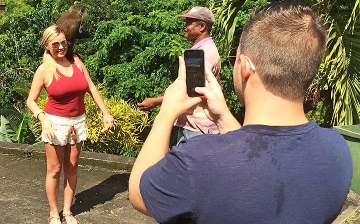 A tourist is having her photo taken with the Mona monkey at Annandale waterfall.