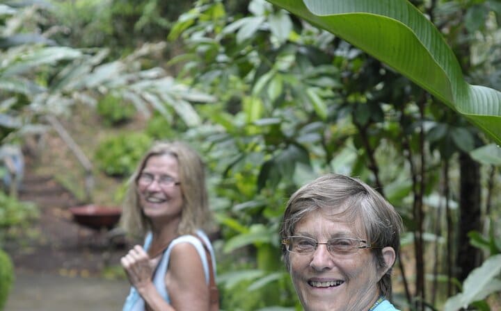 Two senior travellers are thoroughly enjoying this spectacle of nature, walking through the Annandale waterfall.