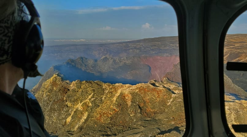 Passenger looking out the window at a large crater