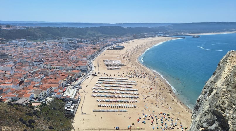 Aerial view of Nazaré beach in Portugal with coastline, ocean waves, and town