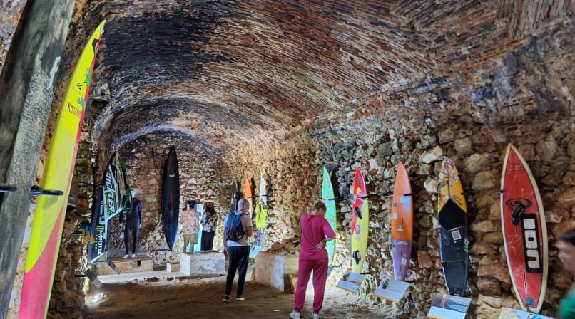 Surfboards displayed inside Nazaré fort museum with visitors observing