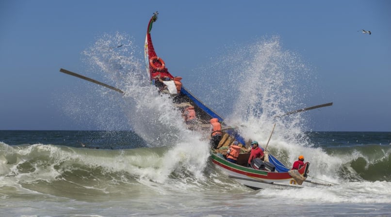 Barco pesquero tradicional cruza olas atlánticas cerca de Aveiro con tripulación
