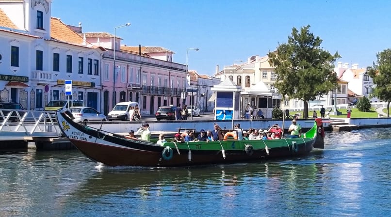 Moliceiro boats on Aveiro canal with colorful waterfront buildings and passengers