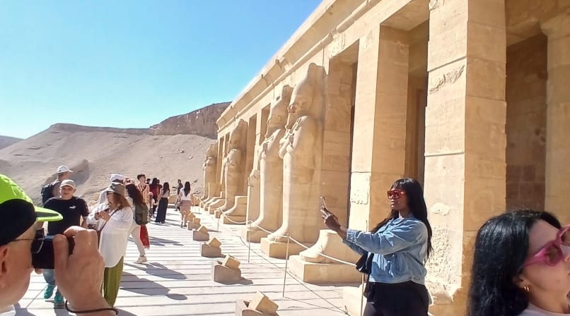 Tourists taking photos along the stone pillared balcony of Hatshepsut Temple in Luxor