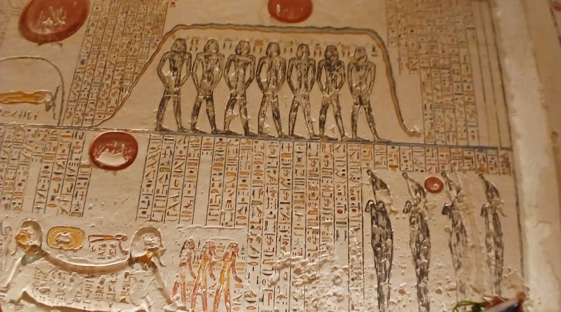 Detailed Egyptian tomb wall showing painted deities and hieroglyphics in yellow red ,and black tones