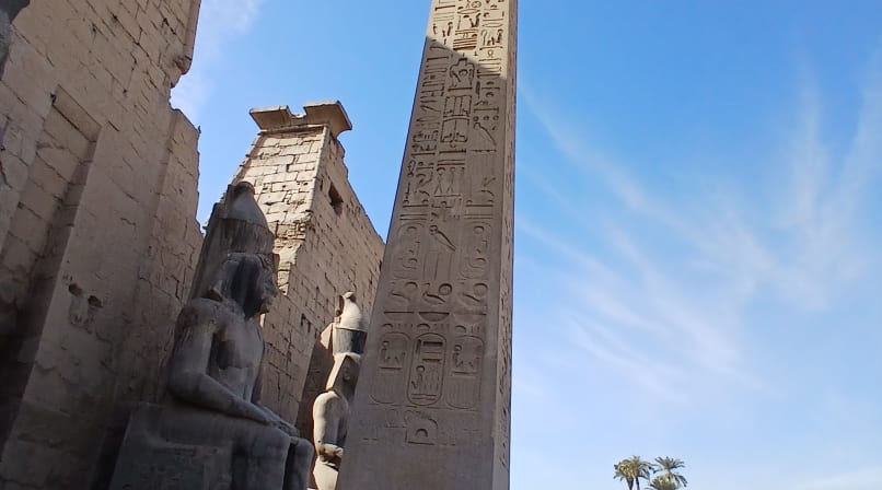Front view of Luxor Temple with two colossal statues of Ramses II and the ancient granite obelisk in Luxor, Egypt.