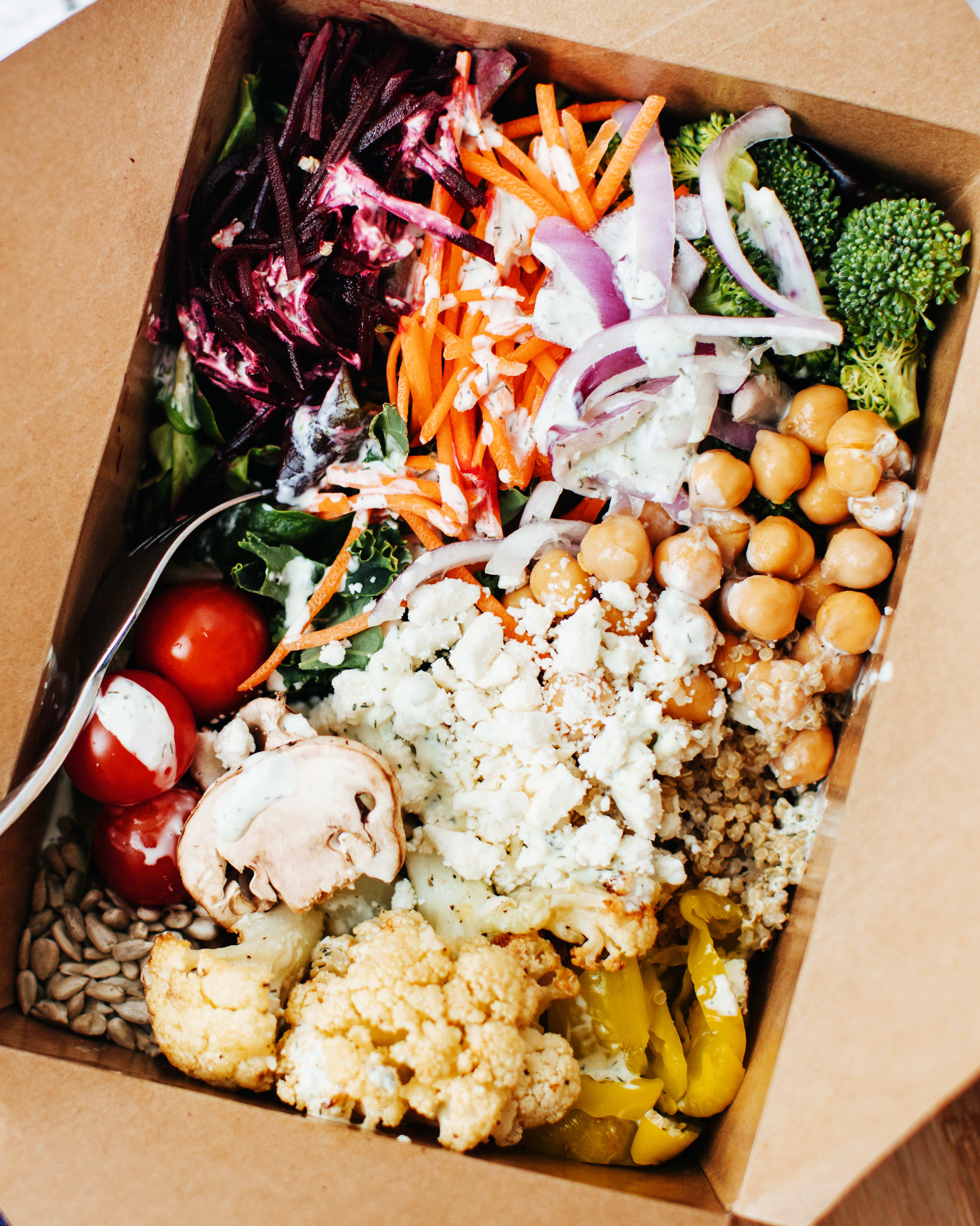An assortment of items from New Seasons salad bar, including cauliflower, mushrooms, carrots, chickpeas, salad, tomatoes and peppers.