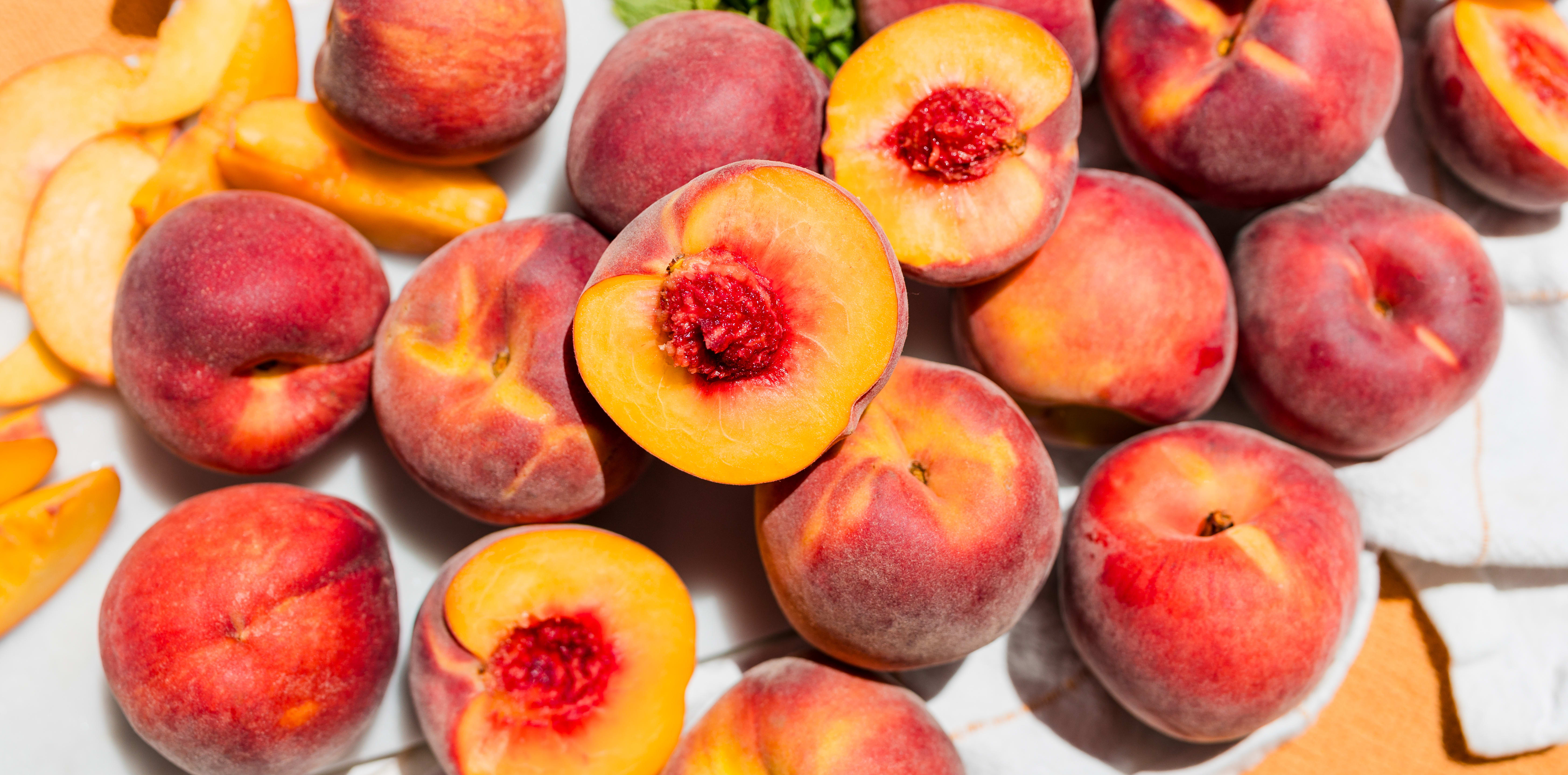 An image of a bunch of local Peaches, some cut in half, some whole, some sliced. 