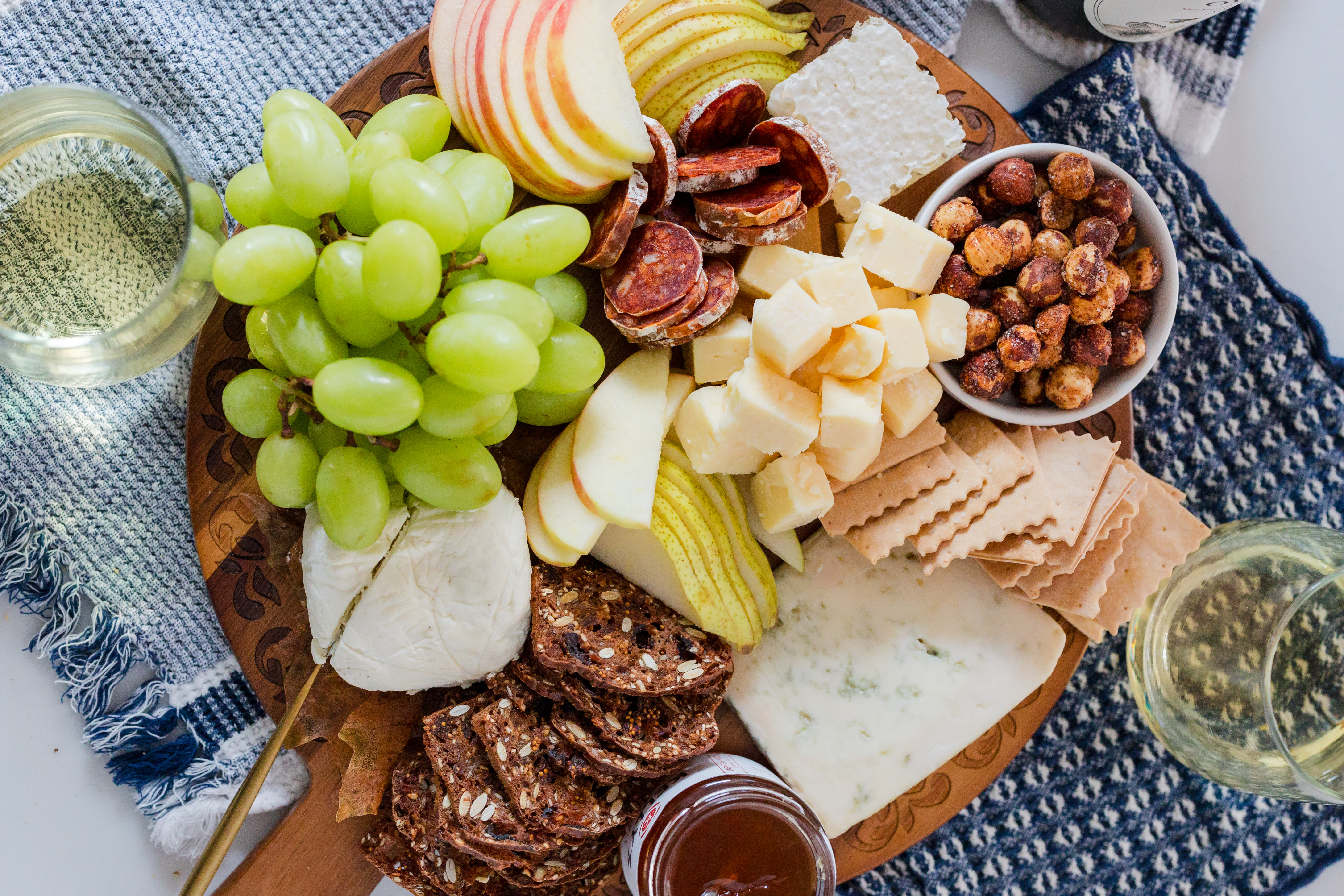 A top donw image of a variety of Oregon Cheeses with grapes, apples, assorted meats, and nuts