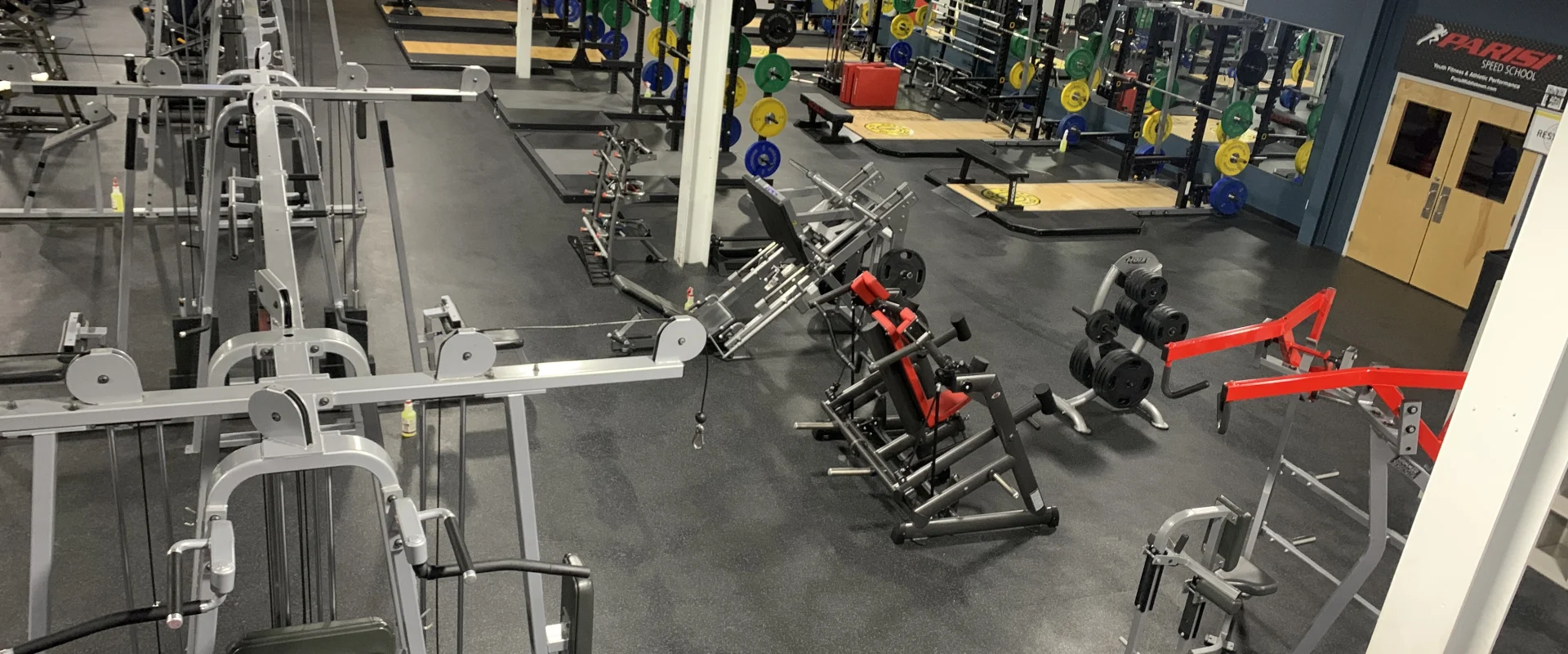 A well-equipped gym with various exercise equipment and machines, including weight racks, treadmills, and other fitness apparatus, arranged in a spacious and organized layout.