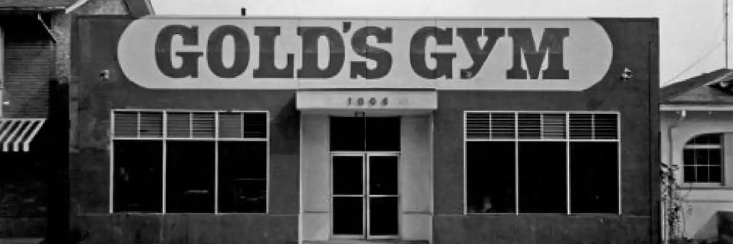 The image shows the exterior of a building with the large text "GOLD'S GYM" prominently displayed on the facade.