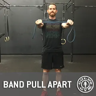 A man wearing a black t-shirt with the text "POLISH POWER" stands in a gym setting, holding resistance bands and performing a band pull apart exercise.