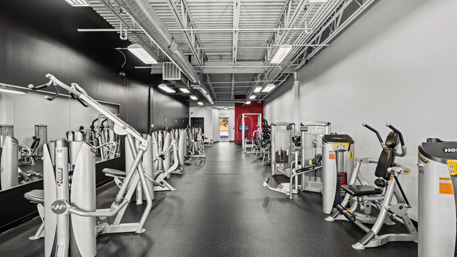 Selectorized strength machines lined along gym wall.