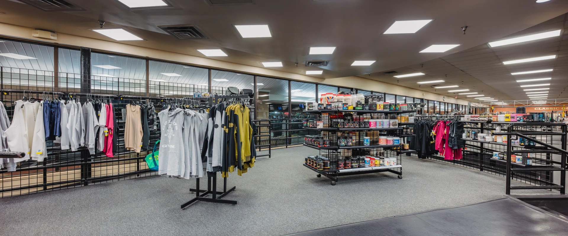 Pro shop at Gold’s Gym in Austin (Southeast), displaying shelves stocked with supplements, protein powders, and energy drinks. Fitness apparel and accessories are organized on racks, with refrigerated coolers holding beverages in the background.