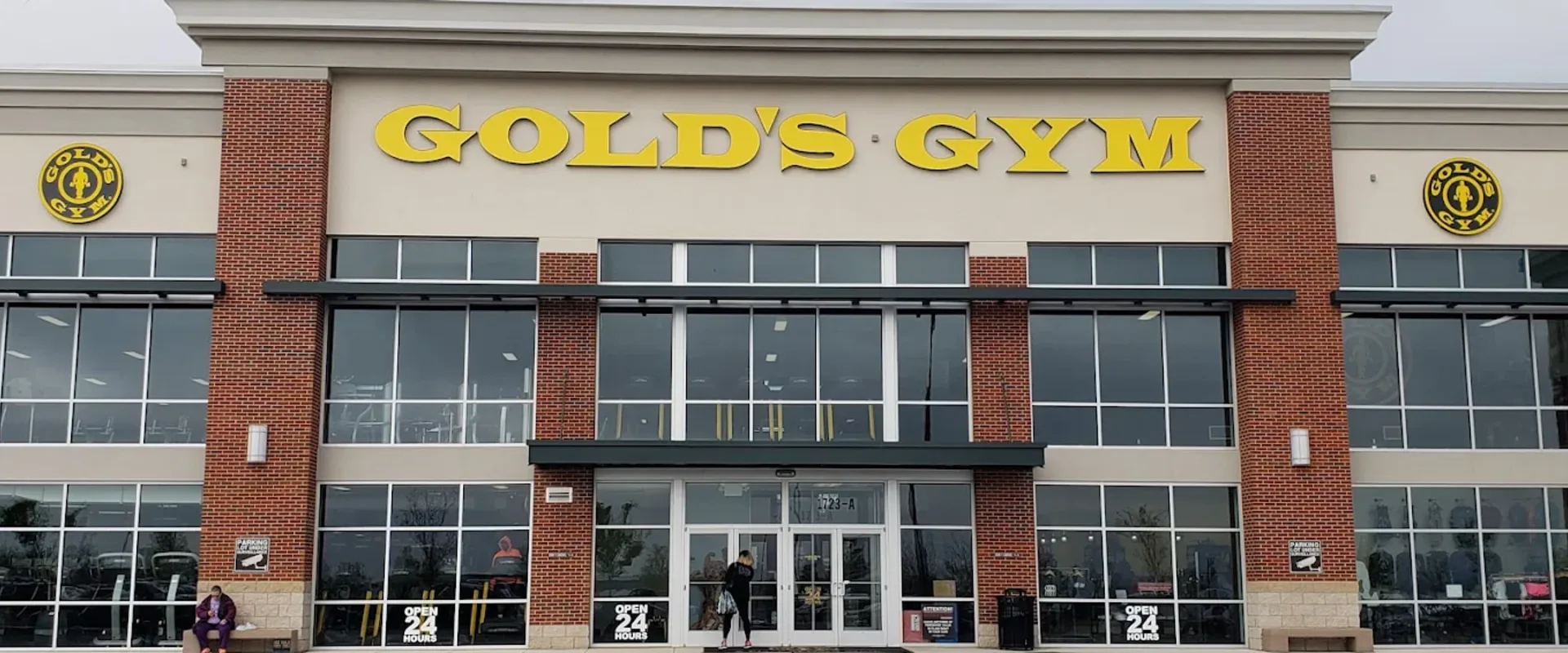 Exterior of Gold’s Gym Capitol Heights with yellow signage, glass windows, and open 24 hours signs at the entrance.