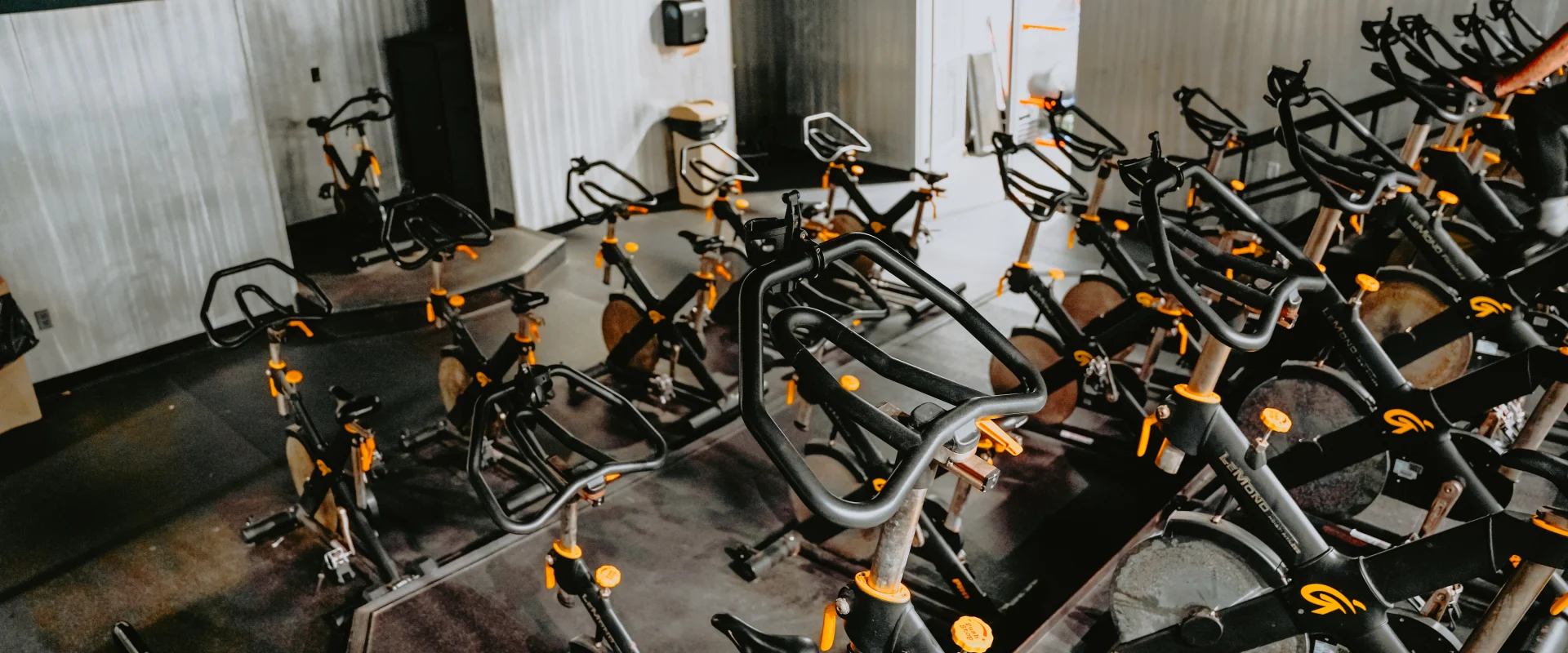 Group cycling room at Gold’s Gym Tennessee, Hixson, featuring rows of stationary bikes arranged on a raised platform. The room has corrugated metal accent walls, dark flooring, and overhead lighting with industrial fixtures.