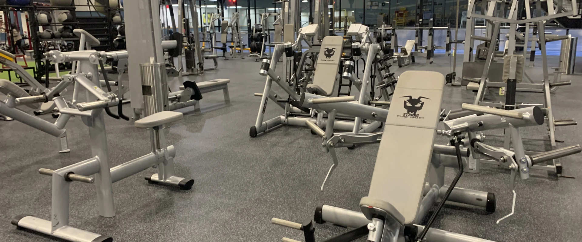 A well-equipped gym with various exercise machines and equipment arranged in a spacious and organized manner, with high ceilings and ample lighting.