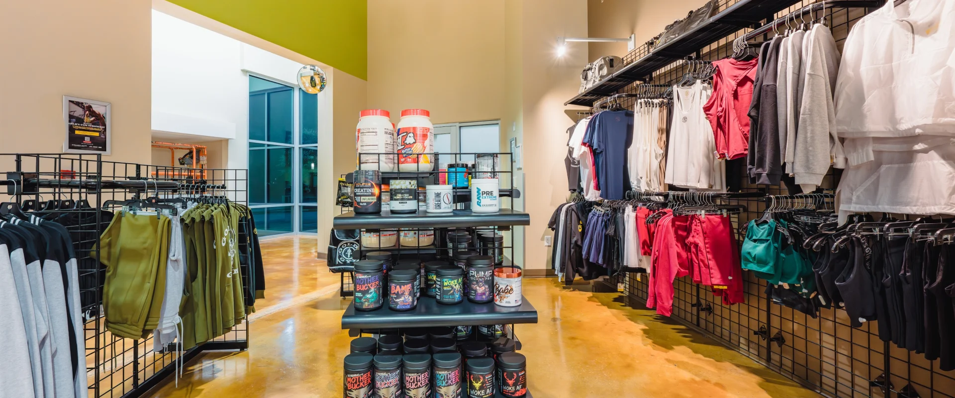 Store interior showcasing a colorful display of workout supplements on center shelves, with racks of activewear and gym bags lining the walls, creating an energetic and motivational atmosphere.