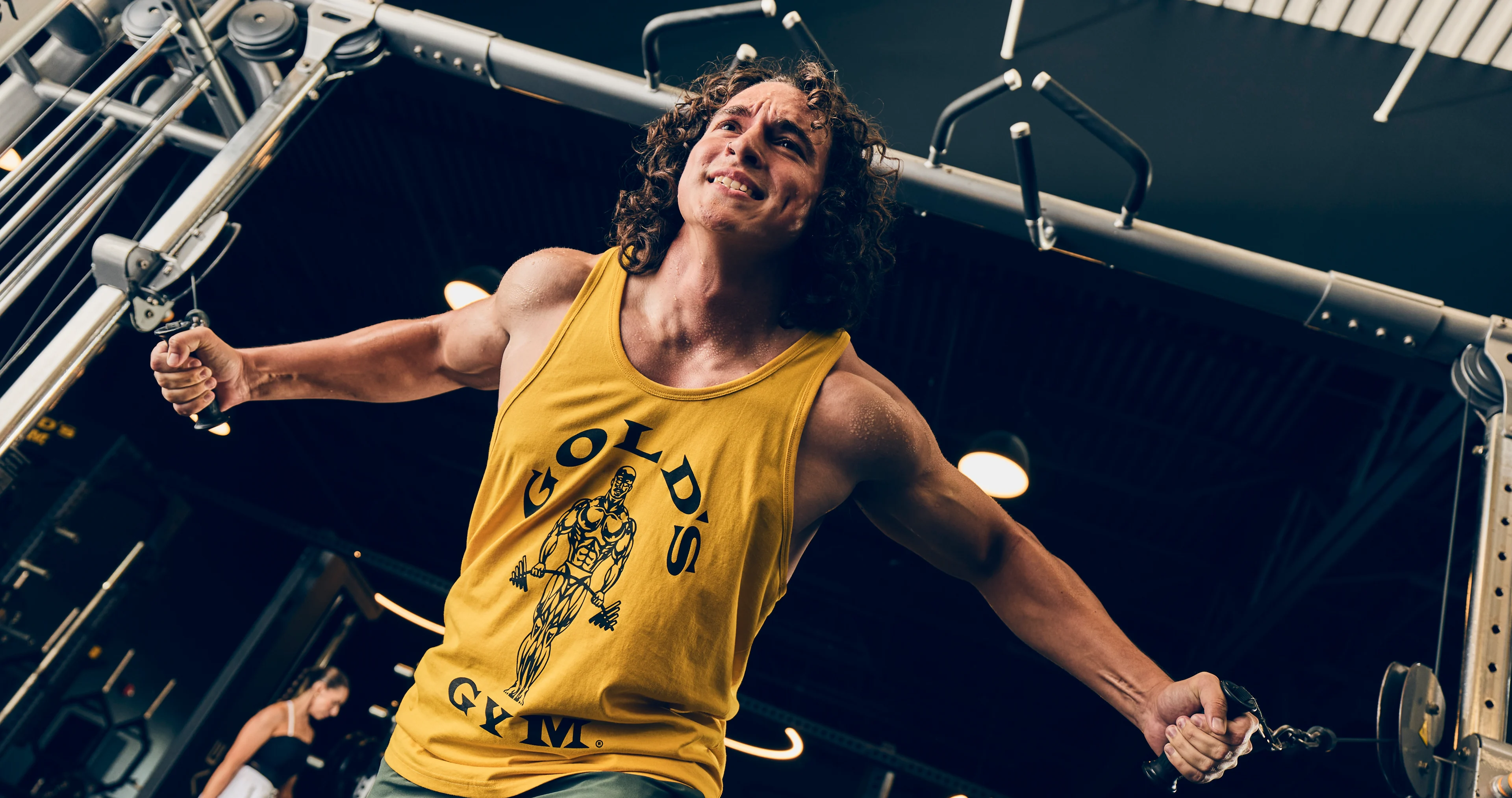 Gold's Gym members smiling and flexing in front of iconic gym backdrop