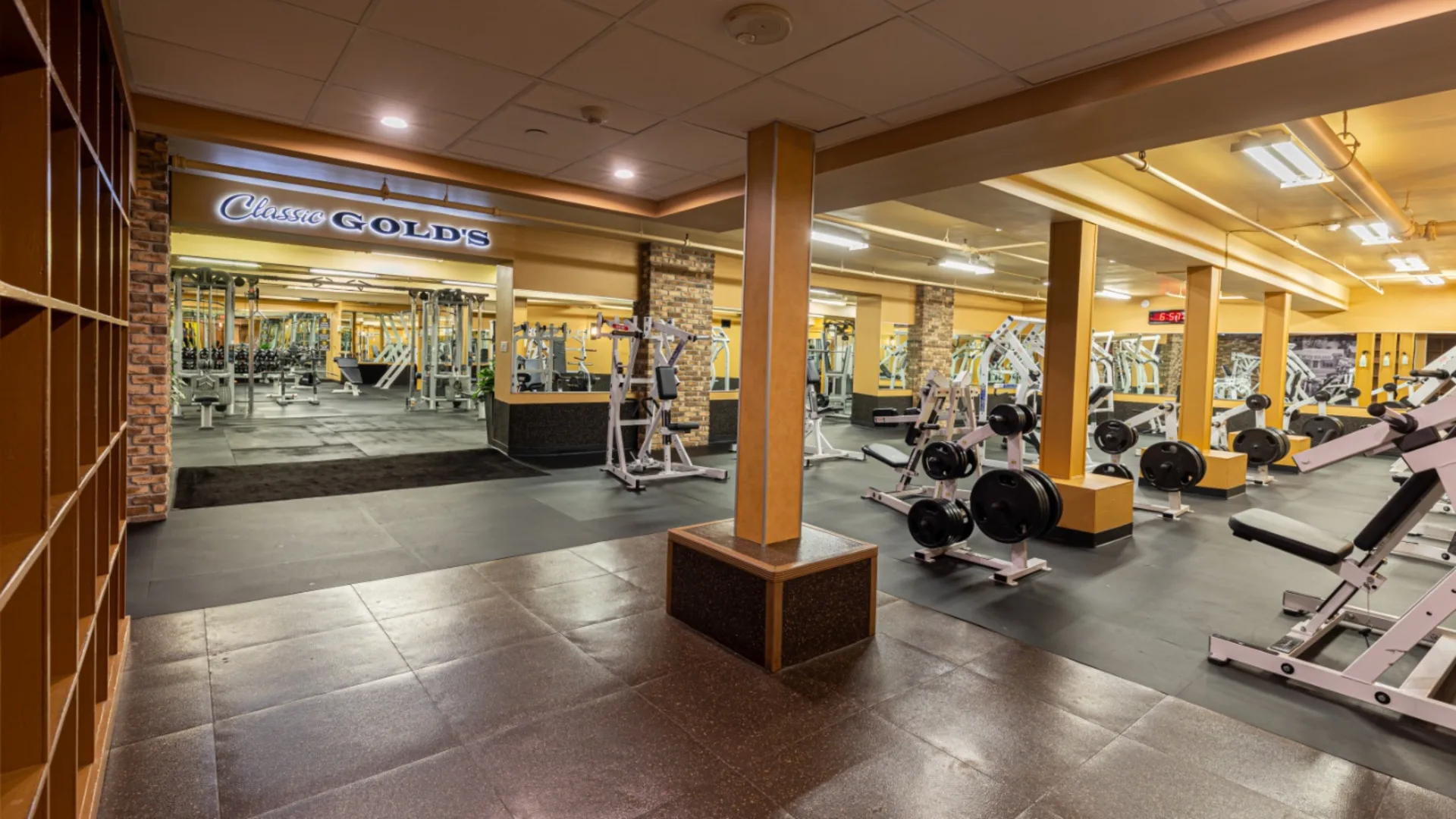 Free weights area at Gold’s Gym New York (East Northport), located in the “Classic Gold’s” section, featuring plate-loaded machines, weight racks, and benches. The space includes mirrored walls, brick accents, and wide walkways for easy movement. Rubber flooring provides a solid foundation for heavy lifting, while overhead lighting brightens the strength-focused environment.