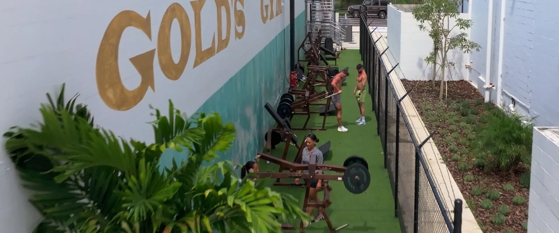 Outdoor turf training area at Gold’s Gym (Gas Worx) with strength equipment and members exercising.