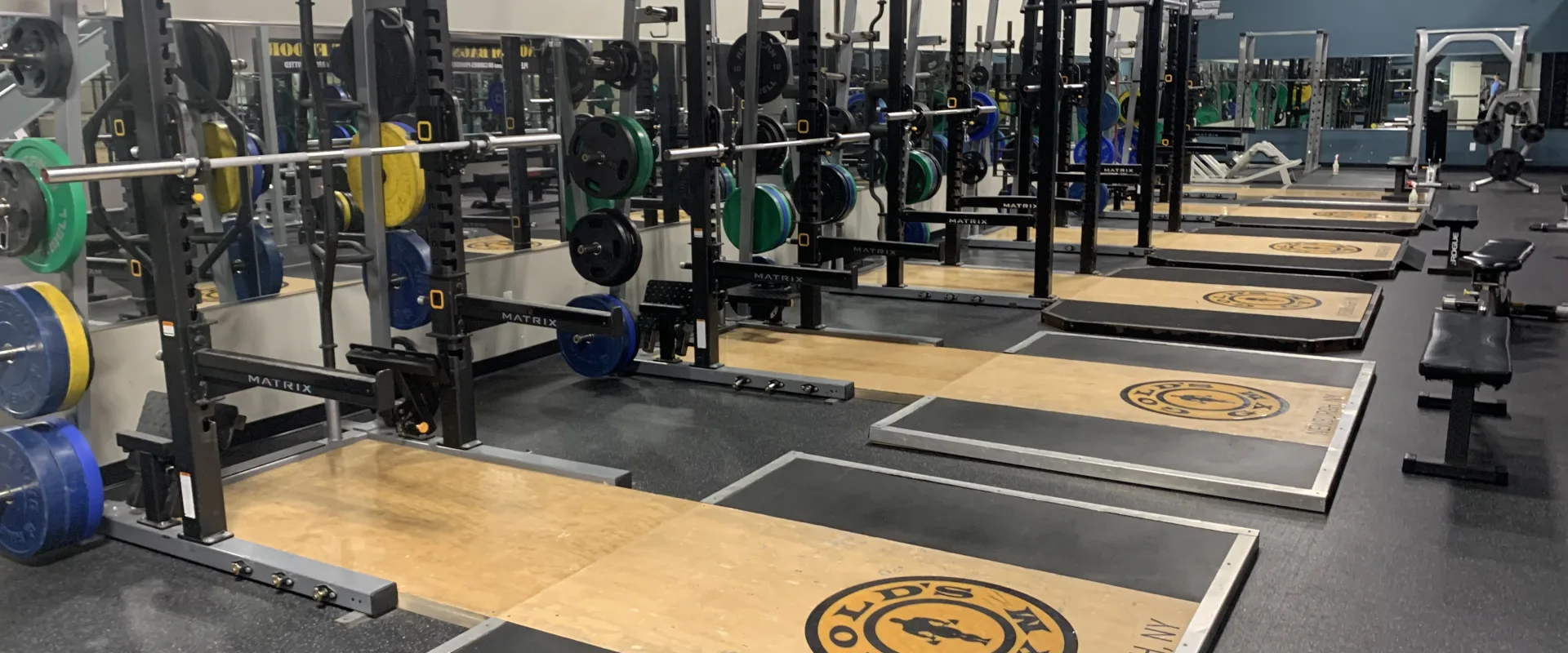 A well-equipped gym with various weight training equipment and machines arranged in a spacious and organized layout.