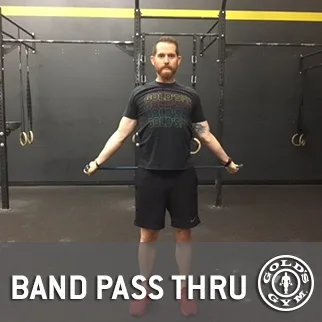 A man stands in a gym setting, wearing a patterned t-shirt and black shorts, with a "Band Pass Thru" sign visible in the background.