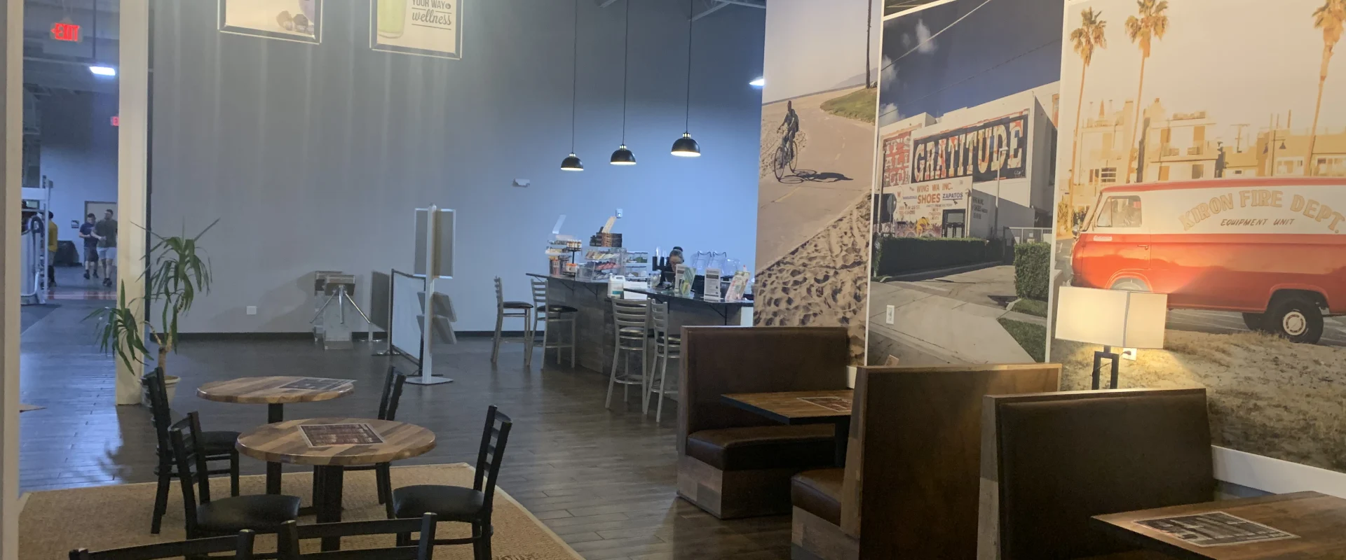 A cozy and inviting cafe interior with wooden tables, chairs, and a large chandelier illuminating the space, along with various decorative elements and artwork on the walls.