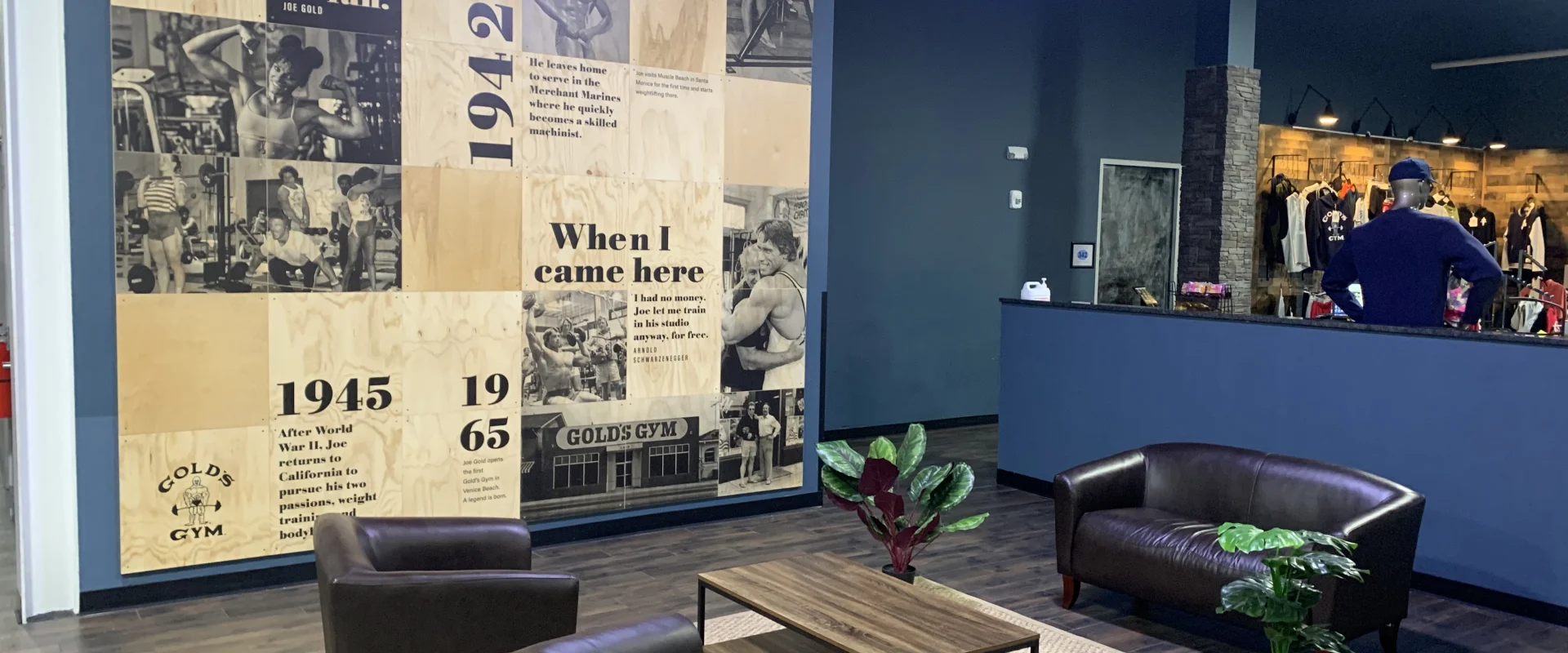 The image depicts a cozy lounge area with leather armchairs and a coffee table, set against a wall displaying a timeline of historical events from 1915 to 1988.