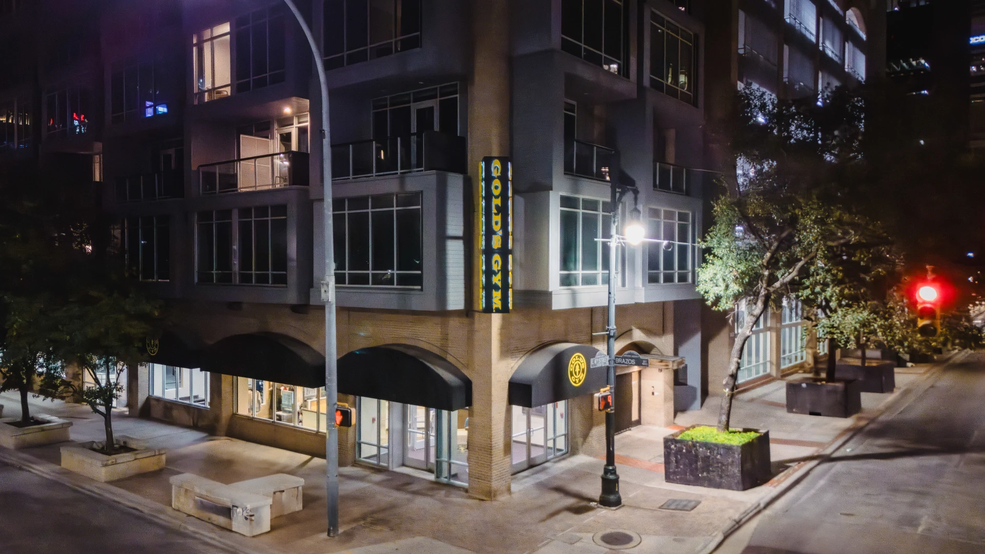 Exterior of Gold's Gym Austin (Downtown) at night time, featuring a modern building design with large windows and a prominent Gold's Gym sign on the facade.
