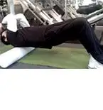 A person is lying on a fitness mat in a gym setting, surrounded by various exercise equipment and machines.