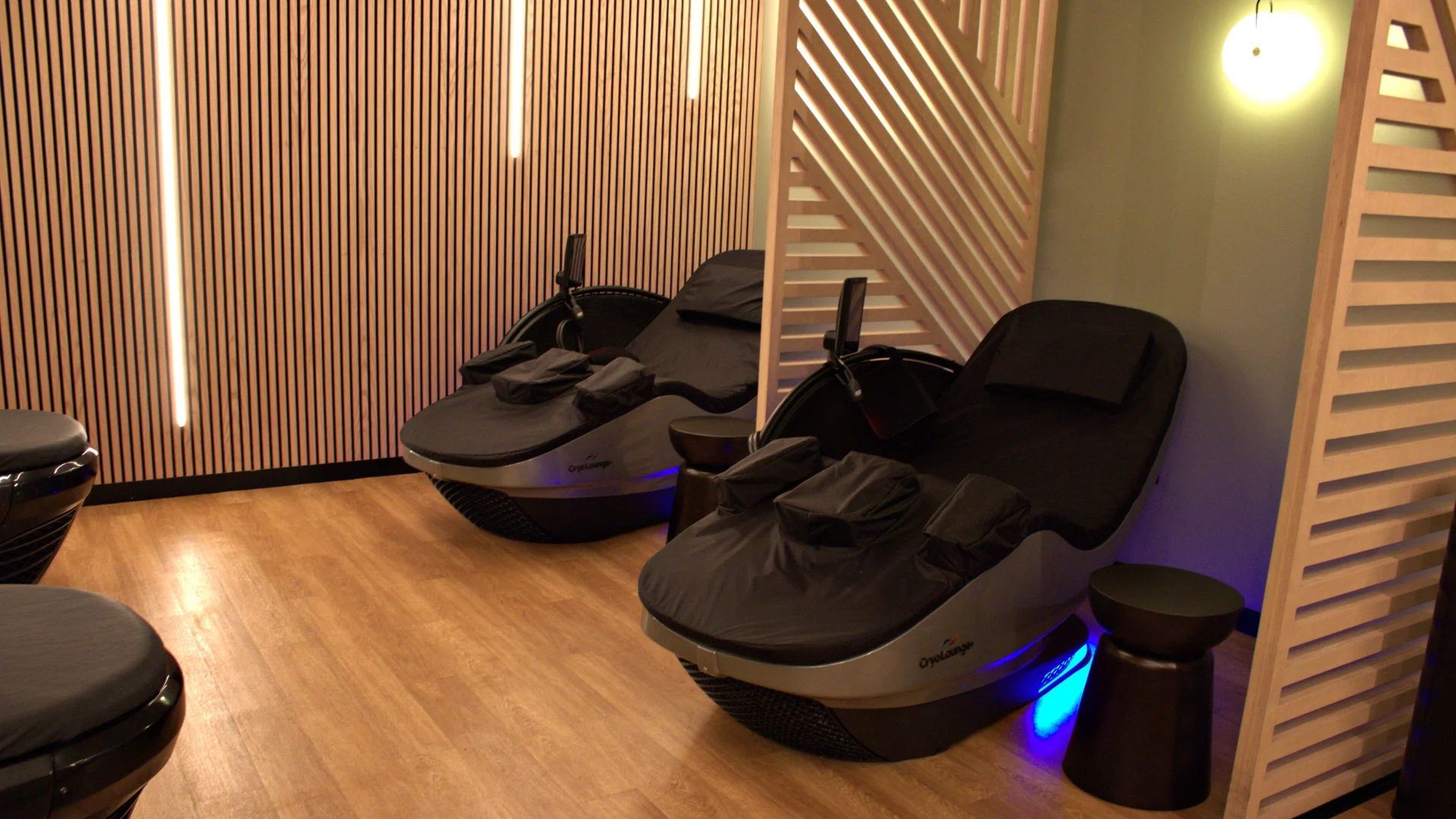 Private recovery area at Gold's Gym Austin, Burnet Rd featuring CryoLounge+ chairs, soft lighting, and slatted wood paneling for a calming, modern vibe.