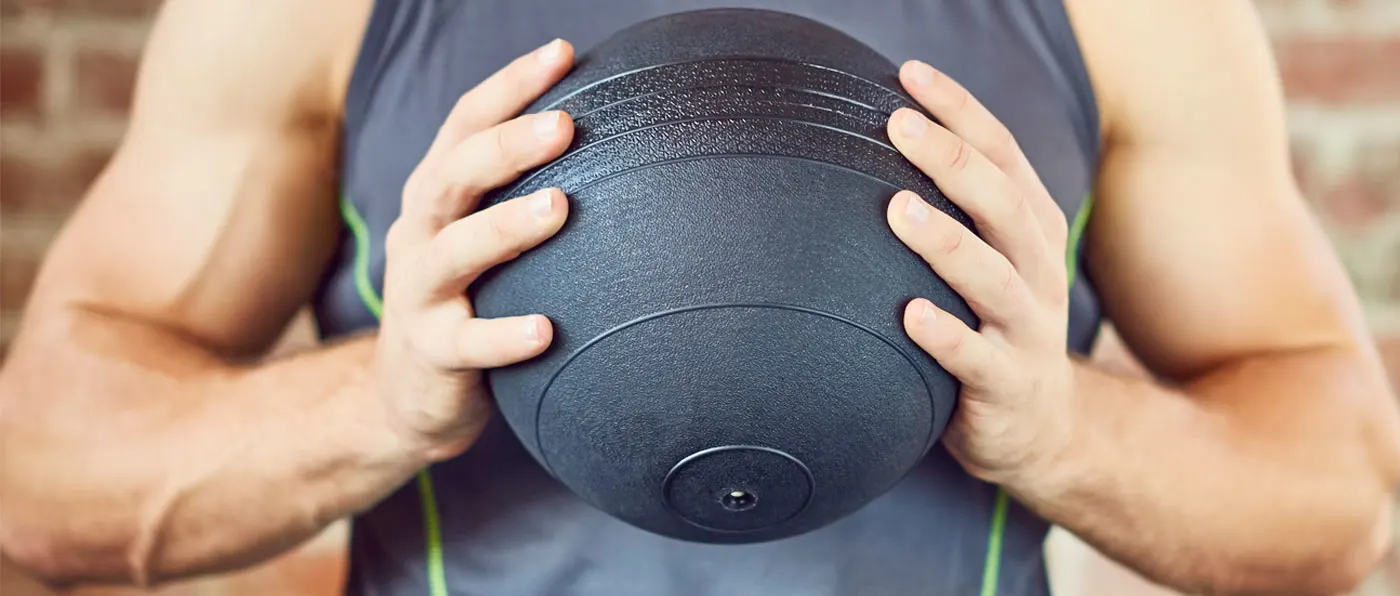 The image shows a person's hands holding a black foam roller against their legs, with a gray background.