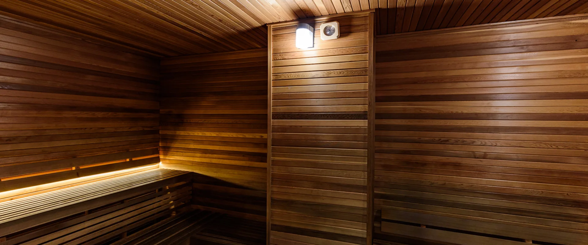 Sauna at Gold’s Gym Long Beach, featuring warm wood paneling and tiered bench seating. A soft glow from recessed lighting enhances the relaxing atmosphere. Designed for post-workout recovery, the sauna provides a space for members to unwind, improve circulation, and support muscle recovery.
