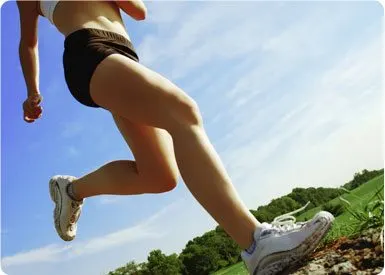 A person in athletic clothing is running on a dirt path surrounded by lush greenery and a cloudy sky.