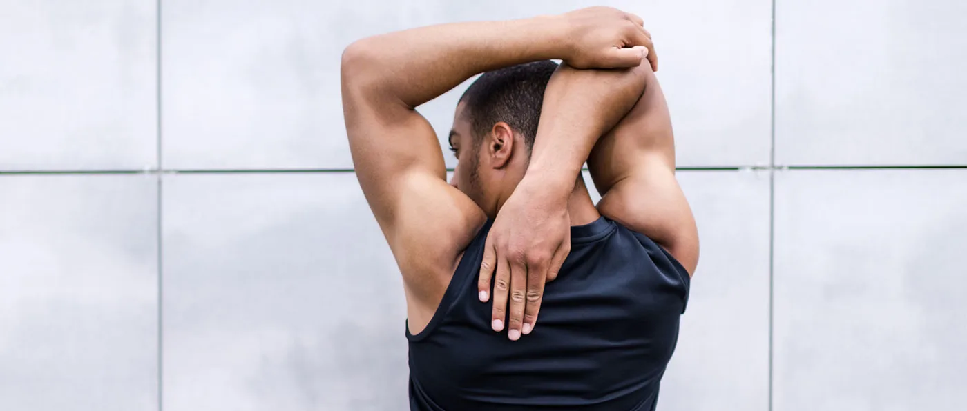 A person in a dark shirt is seen with their arms raised, appearing to be in a state of distress or anguish against a plain white background.