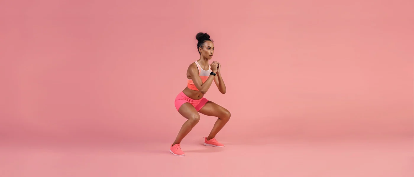 A person wearing bright pink athletic clothing is striking a dynamic pose against a vibrant pink background.