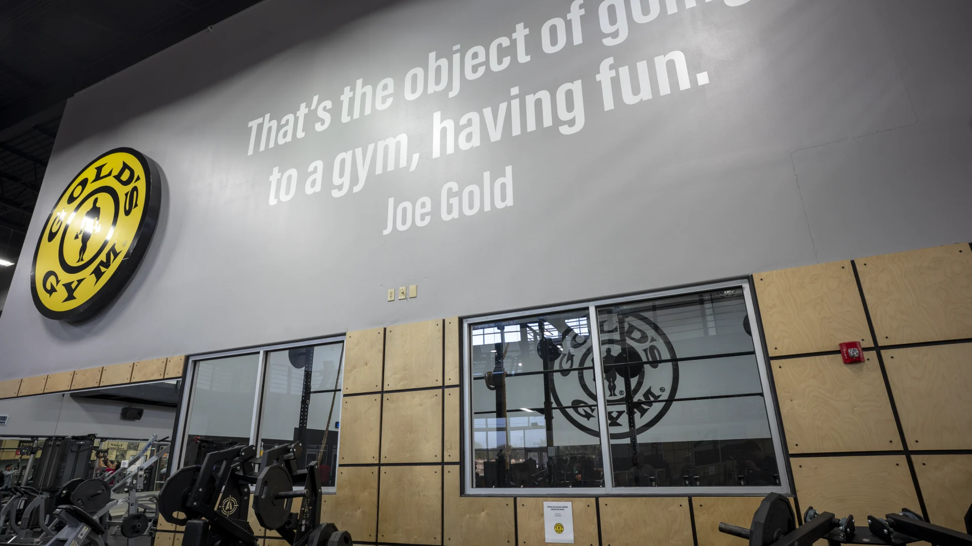 Internal gym wall featuring Gold’s Gym logo and founder Joe Gold’s quote about having fun at the gym. Used for facility branding and website galleries.
