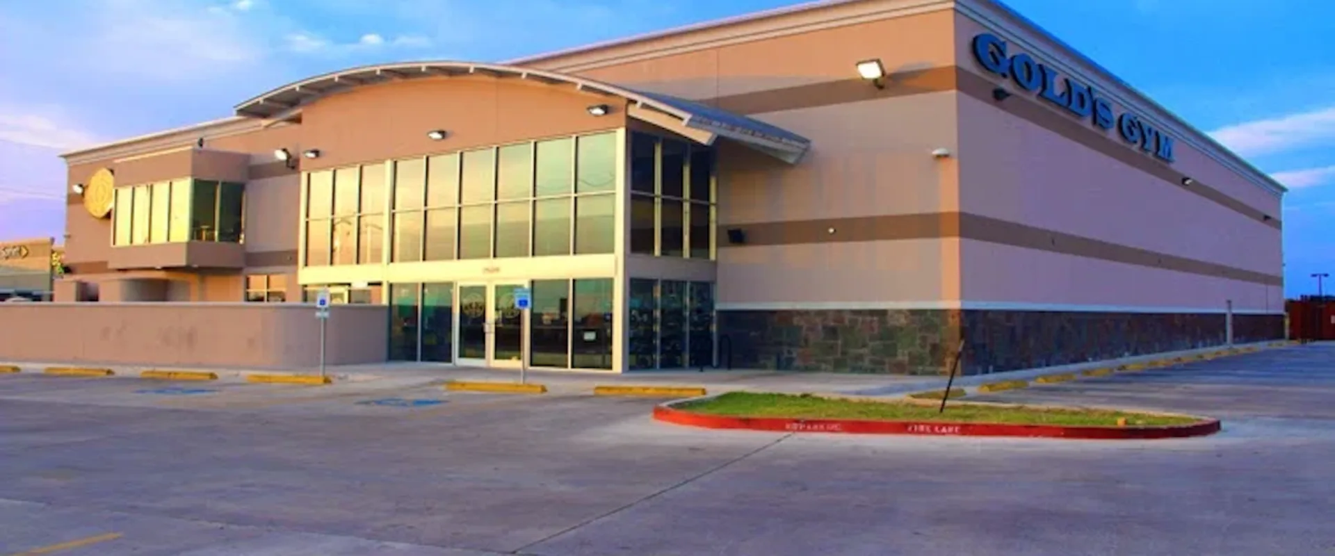 Exterior of Gold’s Gym Mission with large front windows, tan facade, and bright signage above the entrance.