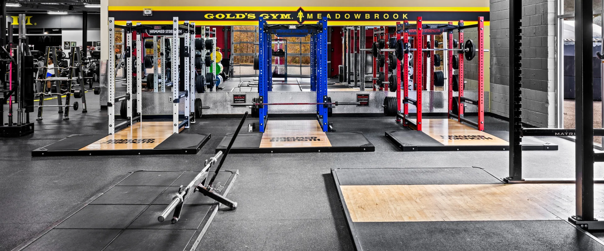Three heavy-duty power racks lined up side by side at Gold’s Gym