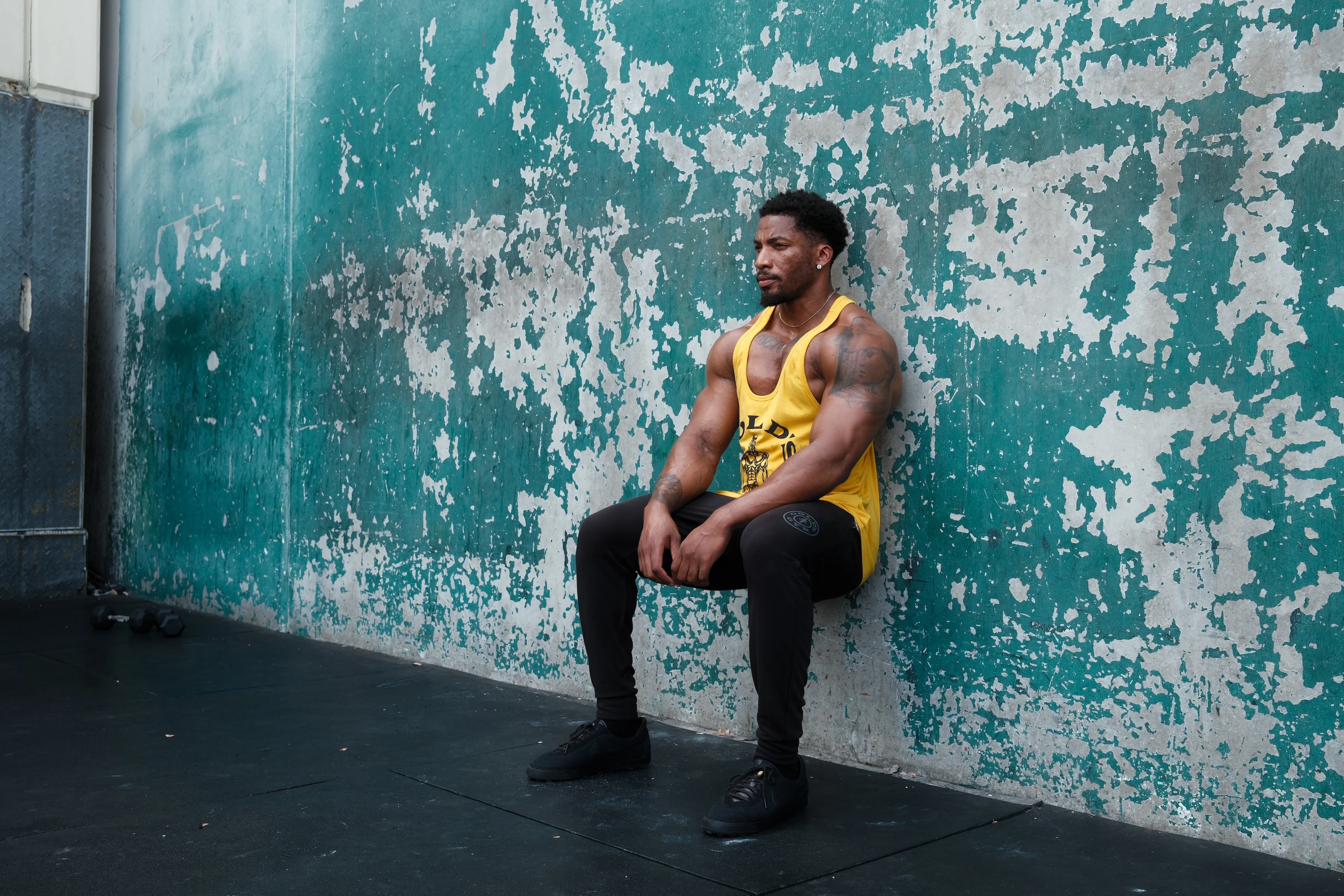 Man holding a wall sit position to strengthen legs and improve endurance.