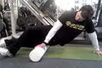 The image shows a person performing a push-up exercise on a fitness mat in what appears to be a gym or workout facility.