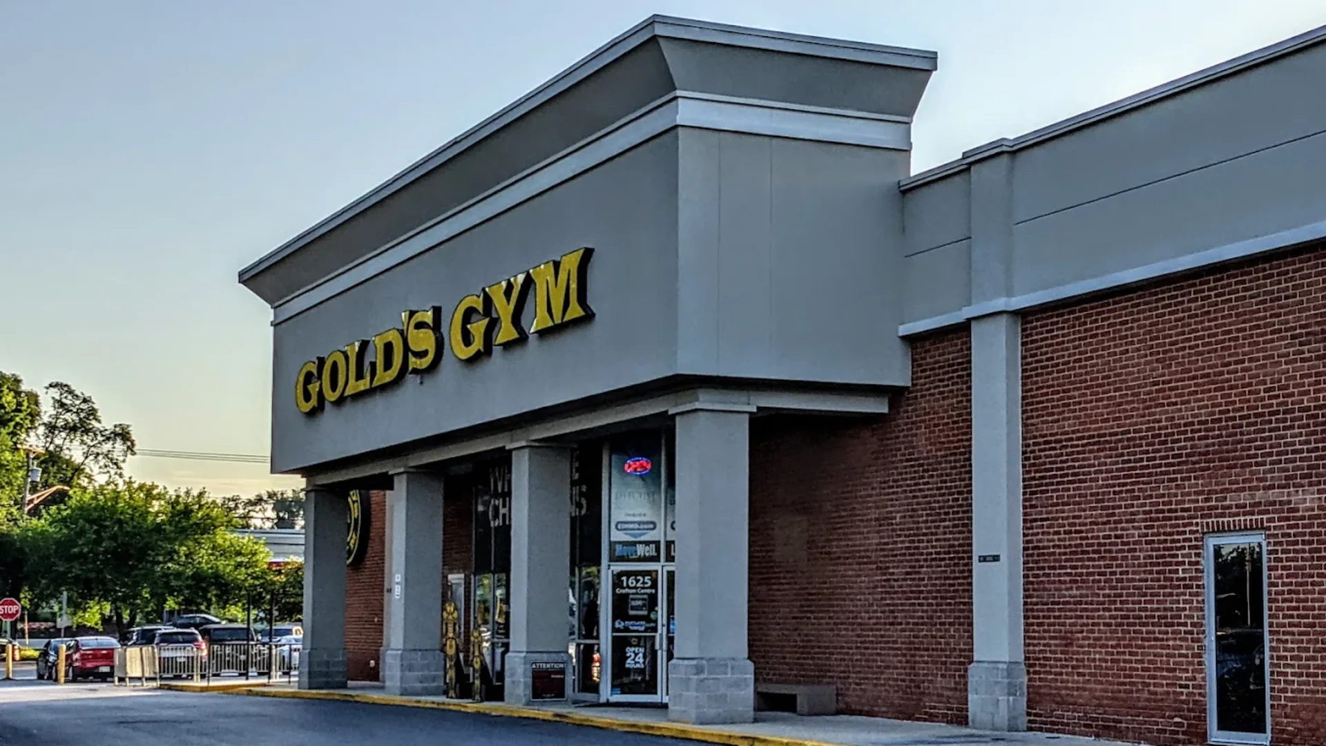 Exterior of Gold’s Gym Crofton with yellow logo above entrance on a brick and gray building.