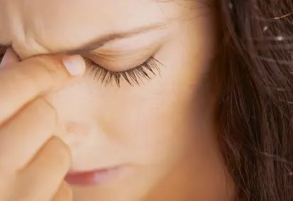 The image shows a close-up of a person's face, with their eyes closed and their hand gently resting on their forehead, suggesting a moment of contemplation or relaxation.