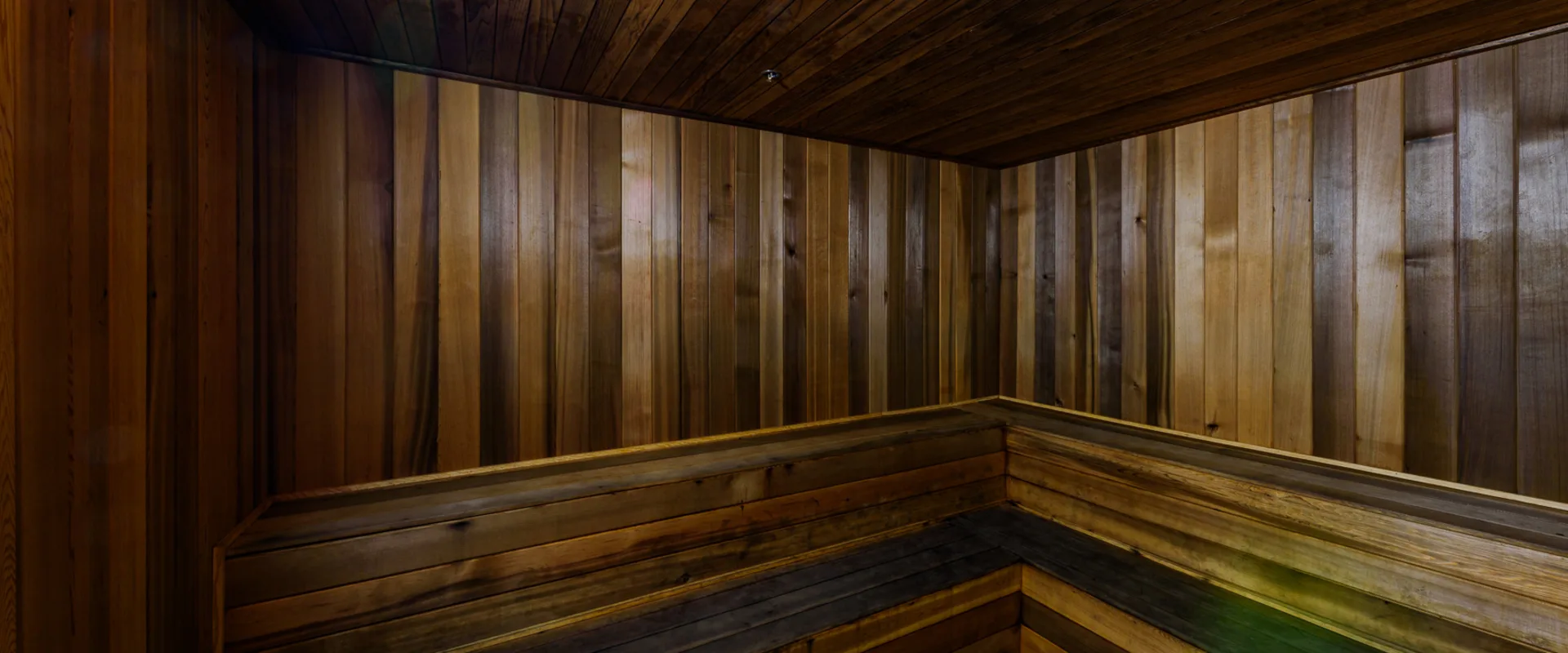 Sauna at Gold’s Gym Thousand Oaks, featuring wooden walls and benches designed for relaxation and post-workout recovery. The heating element sits in the corner, ready to generate soothing heat. The dim lighting and natural wood tones create a calming atmosphere.
