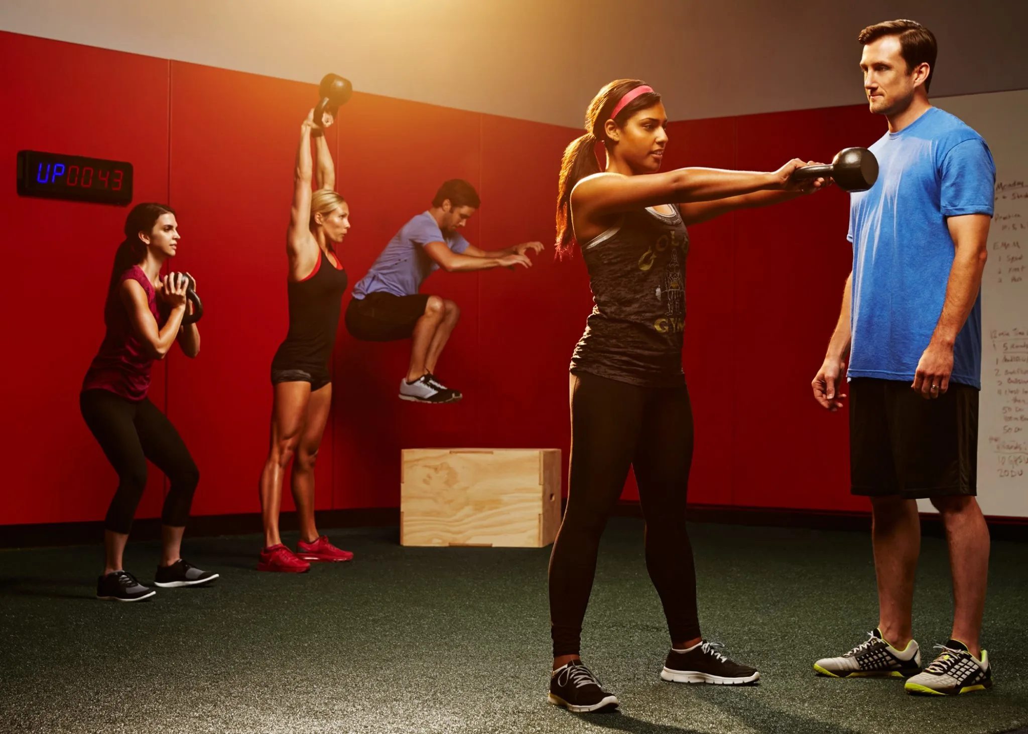 A group of people engaged in physical exercise, with a woman holding a kettlebell in the foreground.