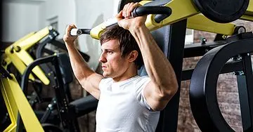 A person is using a weight training machine in what appears to be a gym or fitness center setting.