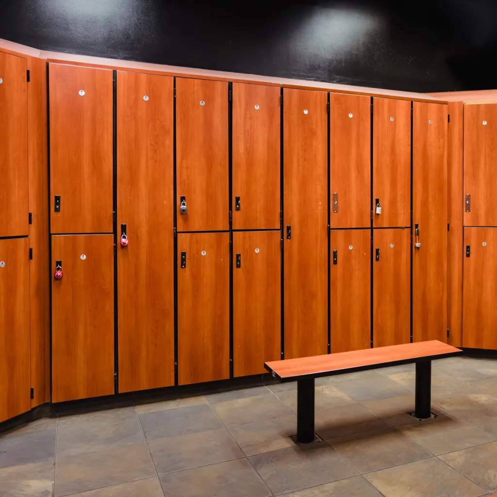 Empty locker room with wooden lockers and a bench on a tiled floor.