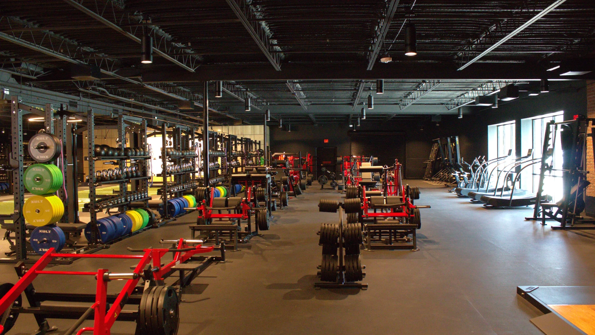 Free weight and powerlifting area at Gold's Gym Austin, Burnet Rd, with squat racks, weight plates, sleds, and a spacious black-ceiling layout built for serious training.