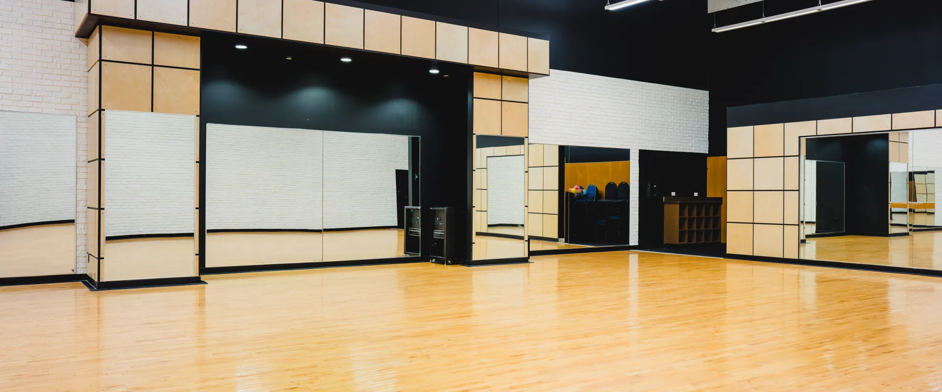Spacious Gold's Gym group exercise studio with polished wooden floors, large mirrors, and modern design elements, ready for fitness classes.